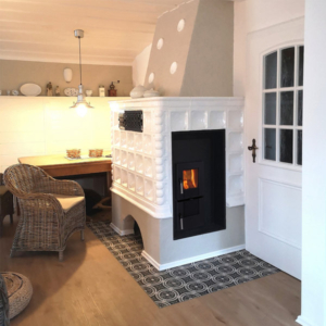 Der moderne Heizeinsatz RUBIN wertet die Kachelofenanlage nicht nur optisch auf, sondern ist auch technisch auf dem neuesten Stand. Denn die Verbrennungstechnik hat in Bezug auf Emissionen und Wirkungsgrad enorme Fortschritte gemacht. Das entlastet die Umwelt und den Geldbeutel, denn das neue Gerät verbraucht wesentlich weniger Brennstoff: Endlich wieder mit gutem Gewissen klimaneutral und umweltfreundlich Heizen. Des Weiteren ist RUBIN bestens für den schnellen Austausch von Altgeräten konzipiert. Er ist in verschiedenen Größen mit unterschiedlichen Frontplatten-Abmessungen erhältlich. Außerdem können die Frontmaße durch die Verwendung von Guss-Anbauleisten auf ein Wunschmaß erweitert werden. Wie vielleicht vom alten Heizgerät gewöhnt, ist RUBIN mit einem Rost innen auch für die Verbrennung von Braunkohlebrikett geeignet und verfügt über einen großen Aschekasten für eine bequeme Reinigung.